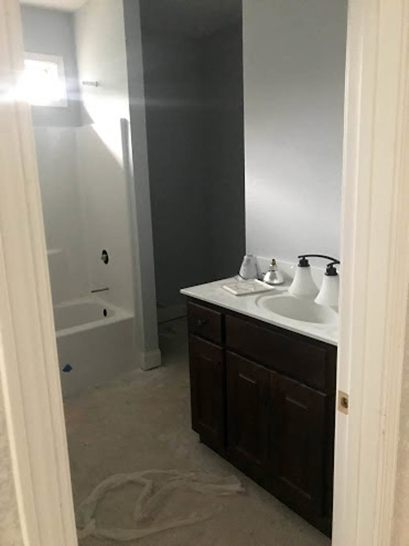 Modern bathroom featuring a white ceramic sink set on a light-colored countertop, freestanding bathtub, tiled walls, and minimalist cabinetry with chrome fixtures.