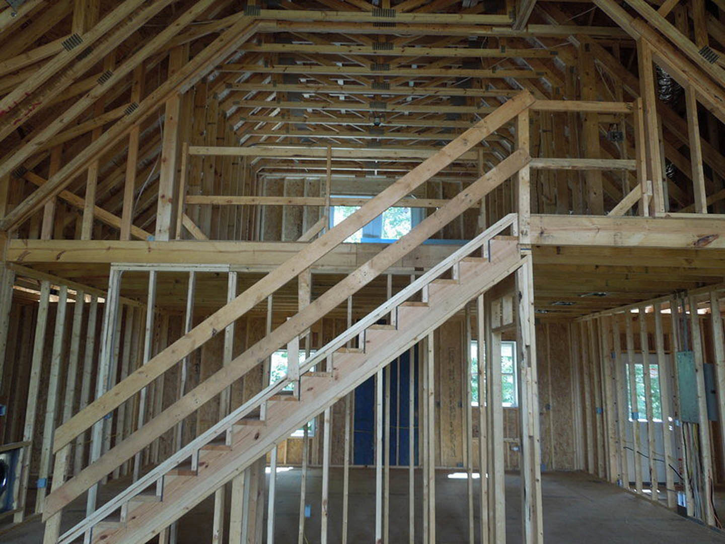 Wooden staircase with natural wood beams, blue accent wall, and large window in modern residential interior