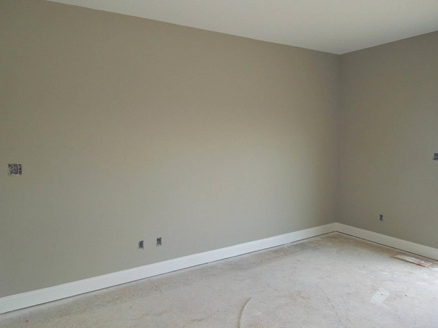 Modern room with smooth white plaster walls, white flooring, simple ceiling molding, and minimalist interior design