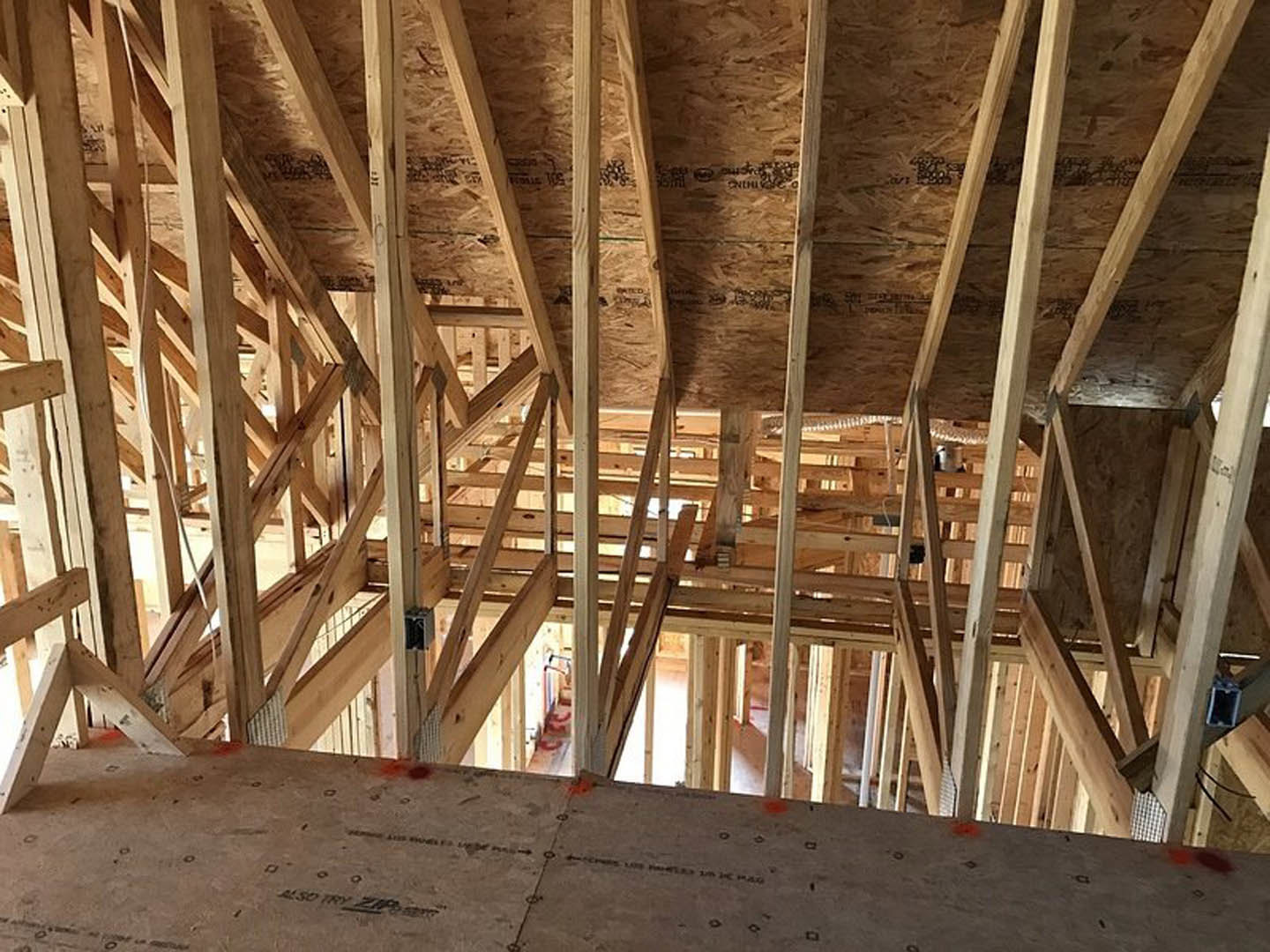 Exposed wood ceiling beams above unfinished concrete floor in residential construction interior
