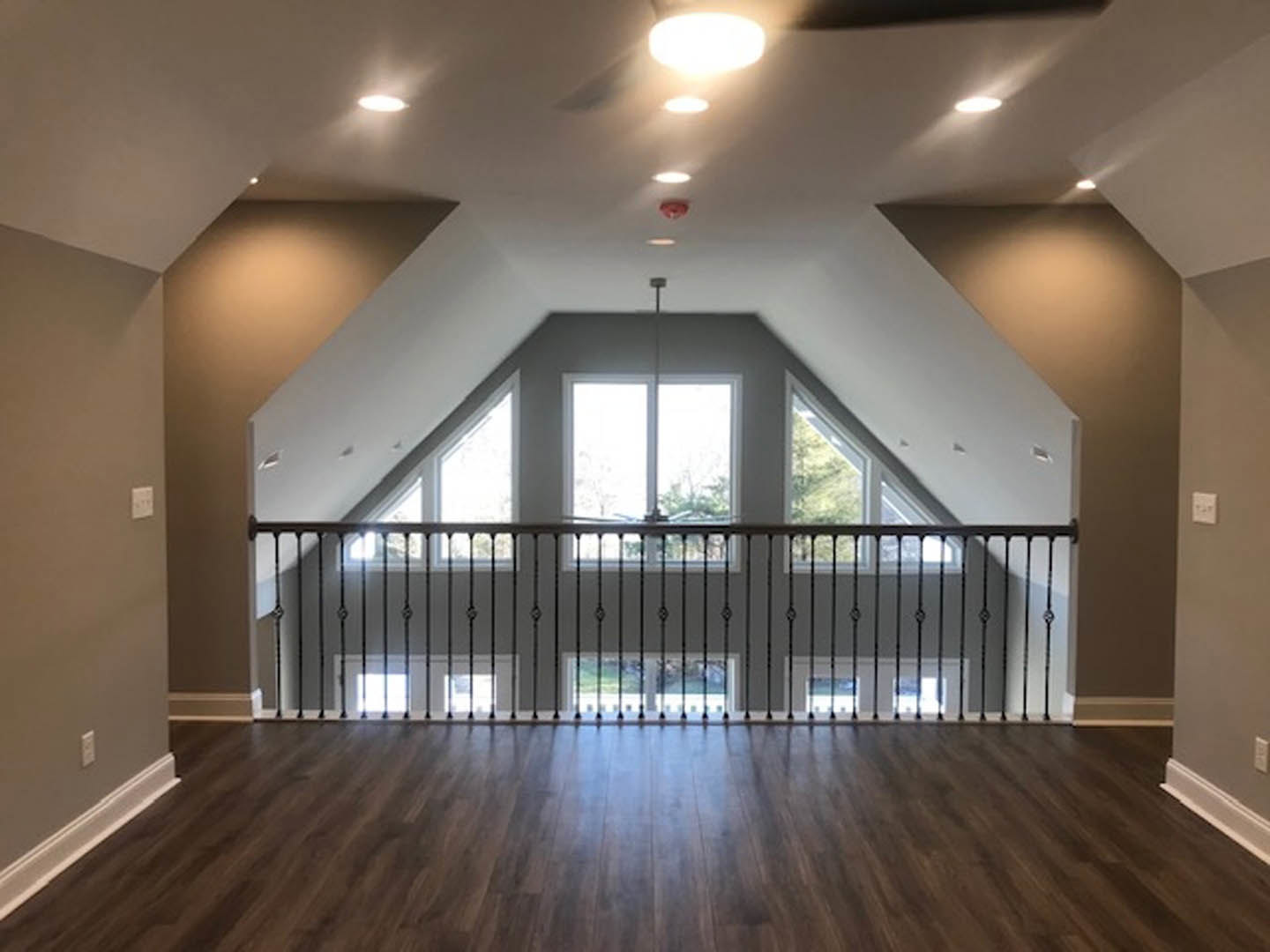 Wood plank flooring, metal handrail, large window with daylight streaming in, white walls, modern interior detailing