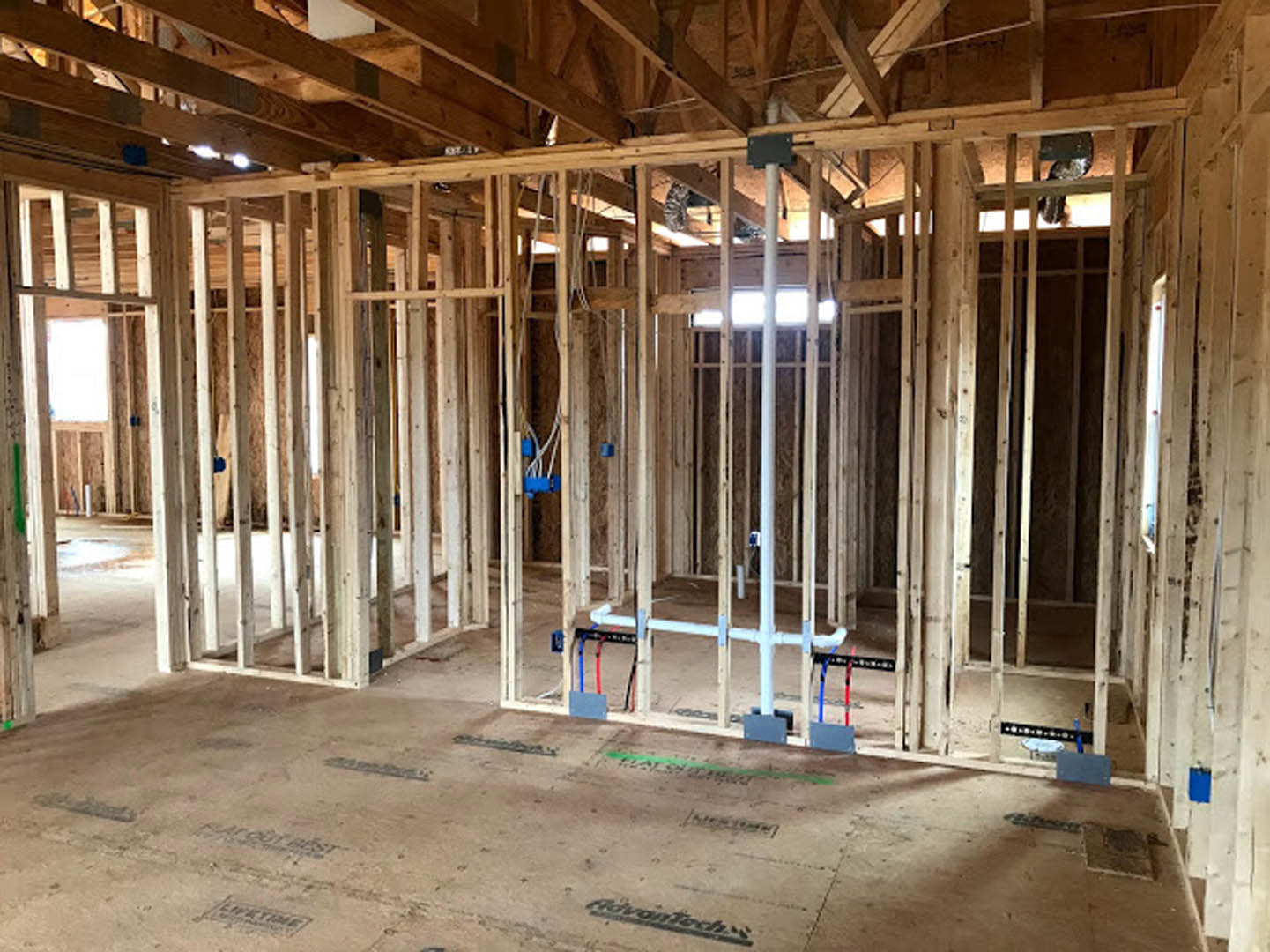 Exposed wooden beams and framing with visible ceiling and floor structure during residential home construction
