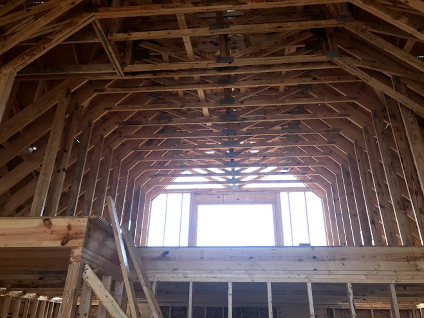 Exposed wooden framing beams with natural finish against white walls inside a residential interior