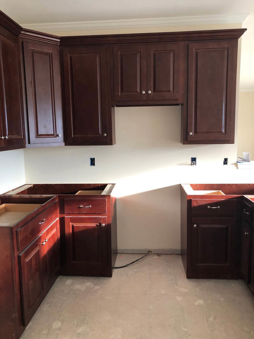 Dark wood kitchen cabinets with sleek hardware, white countertops, and a light ceiling; close-up details of cabinetry and flooring visible.