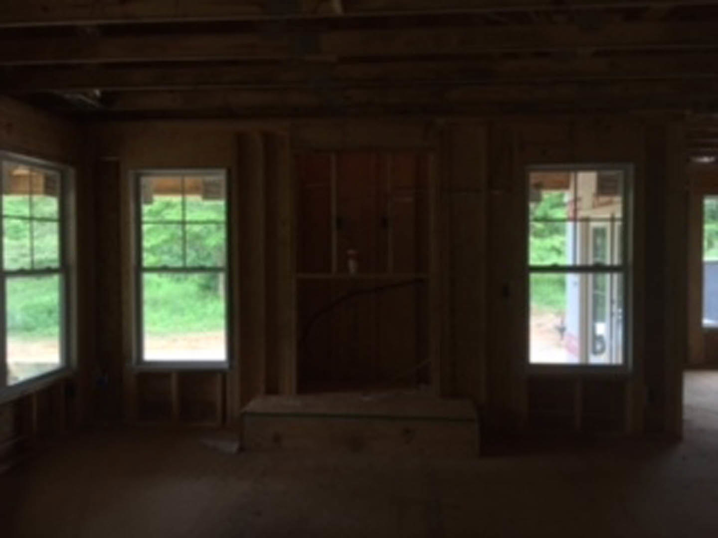 Bright room featuring large windows, exposed wood ceiling beam, light-colored flooring, and views of a green field through the glass.