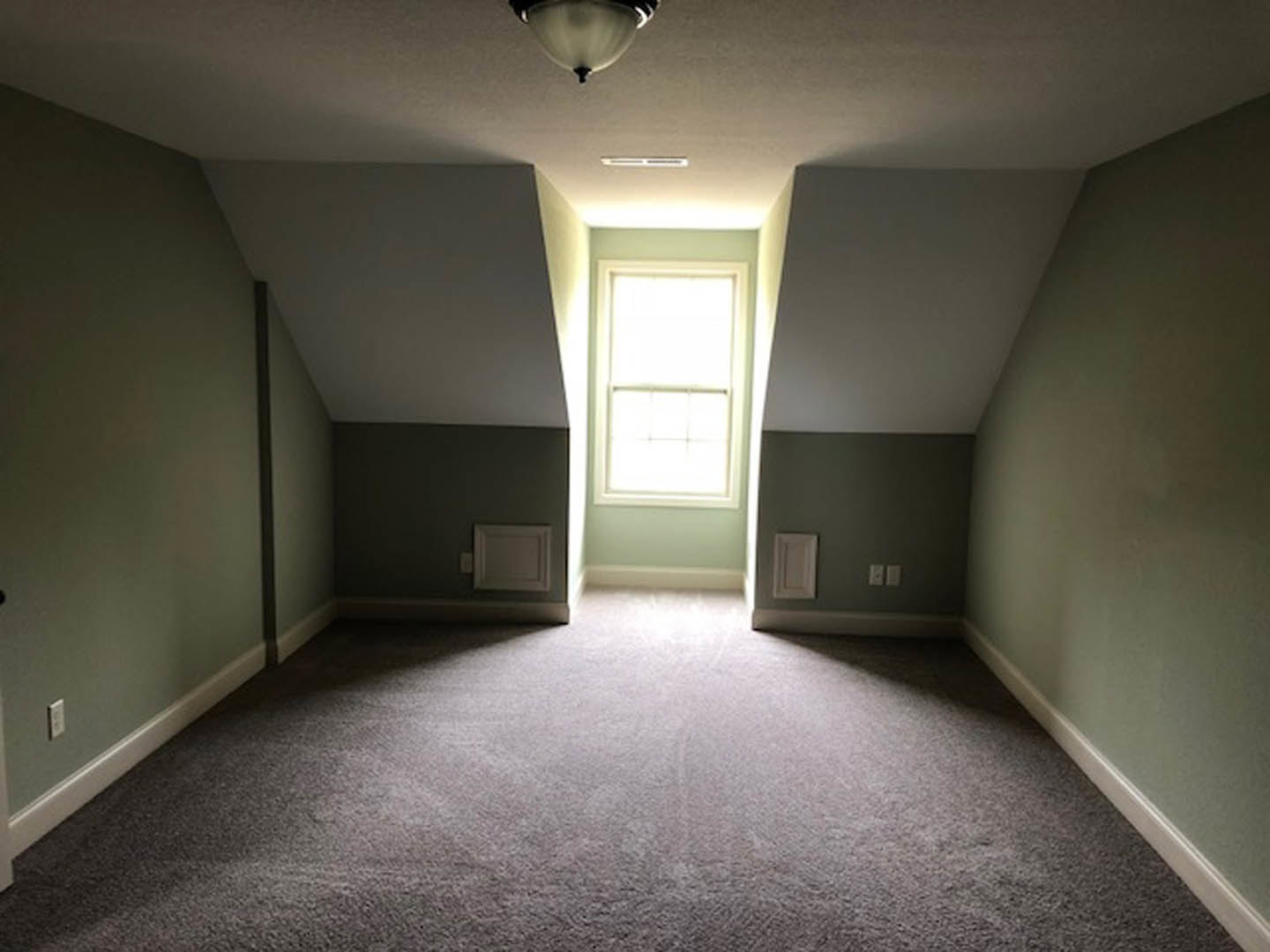 Neutral-toned carpeted room with white walls, square window, recessed ceiling light, and white paneled door