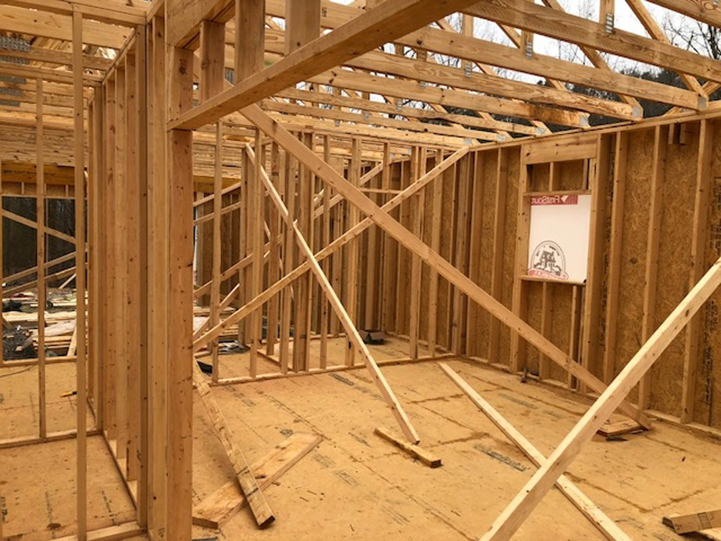 Exposed wooden beams and framing with construction insulation inside a partially built residential home