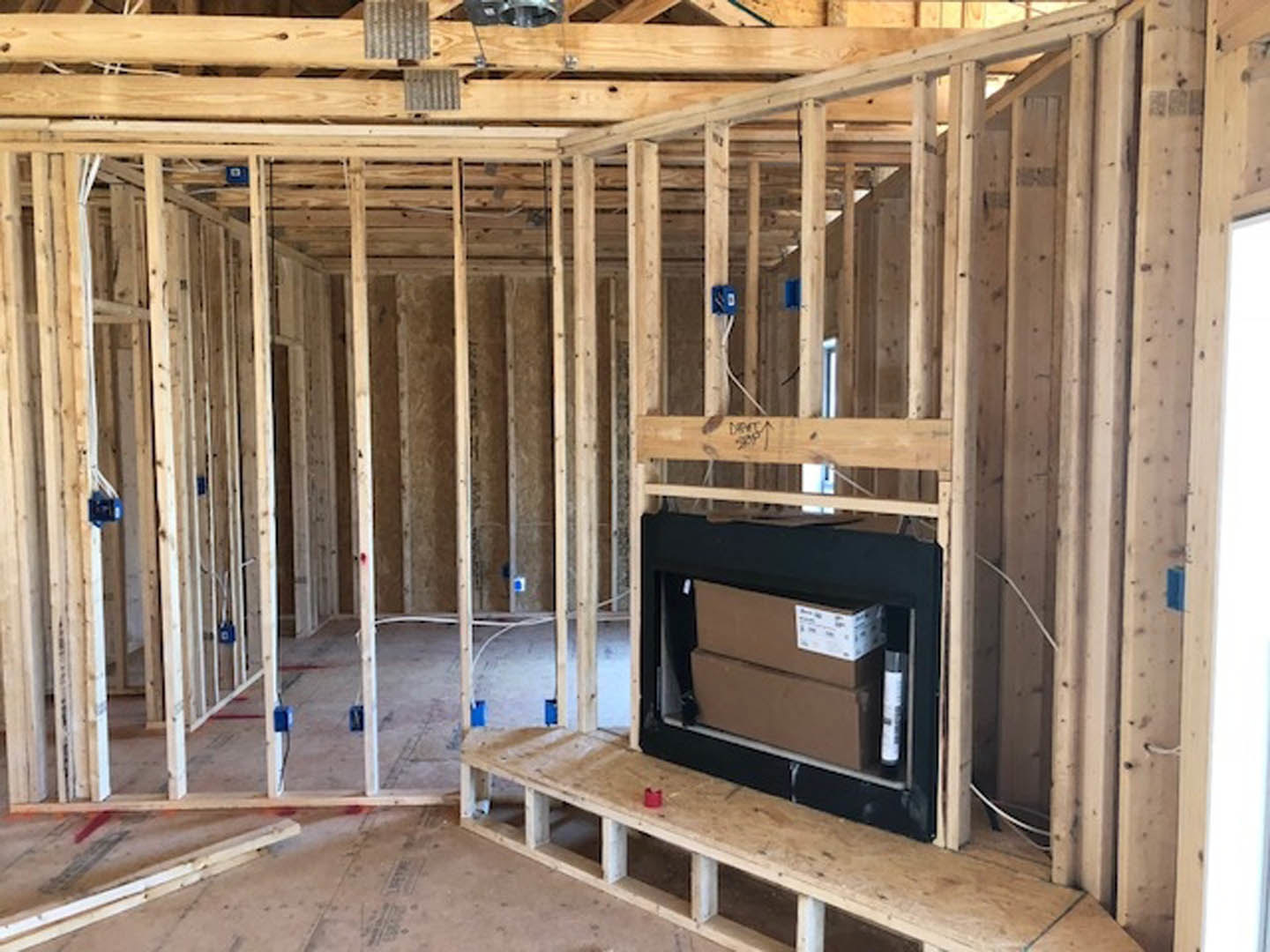 Living room with wood plank flooring, built-in wood shelving, and a stone fireplace surrounded by exposed wood beams