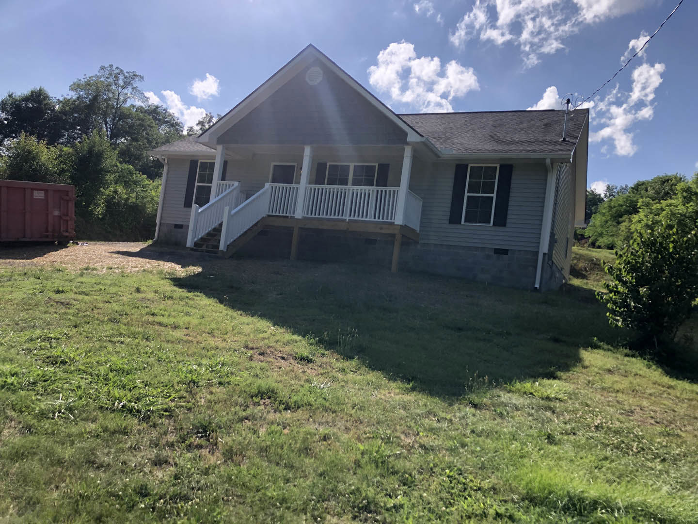 Two-story house with white porch railing, large windows with white frames, manicured lawn, and shrubs in front