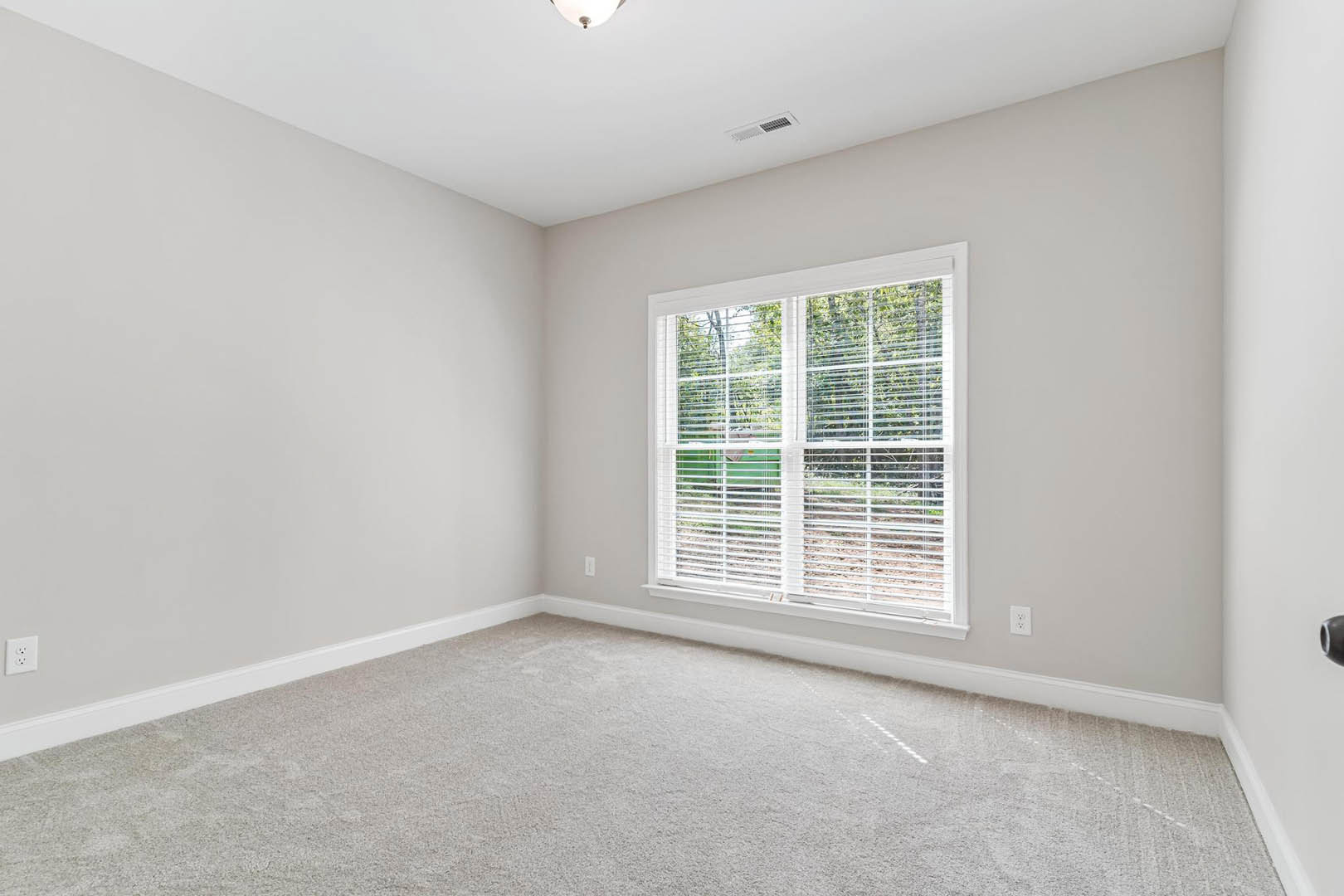 Neutral-toned carpet flooring, white walls, window with horizontal blinds, white ceiling with recessed lighting in a residential room