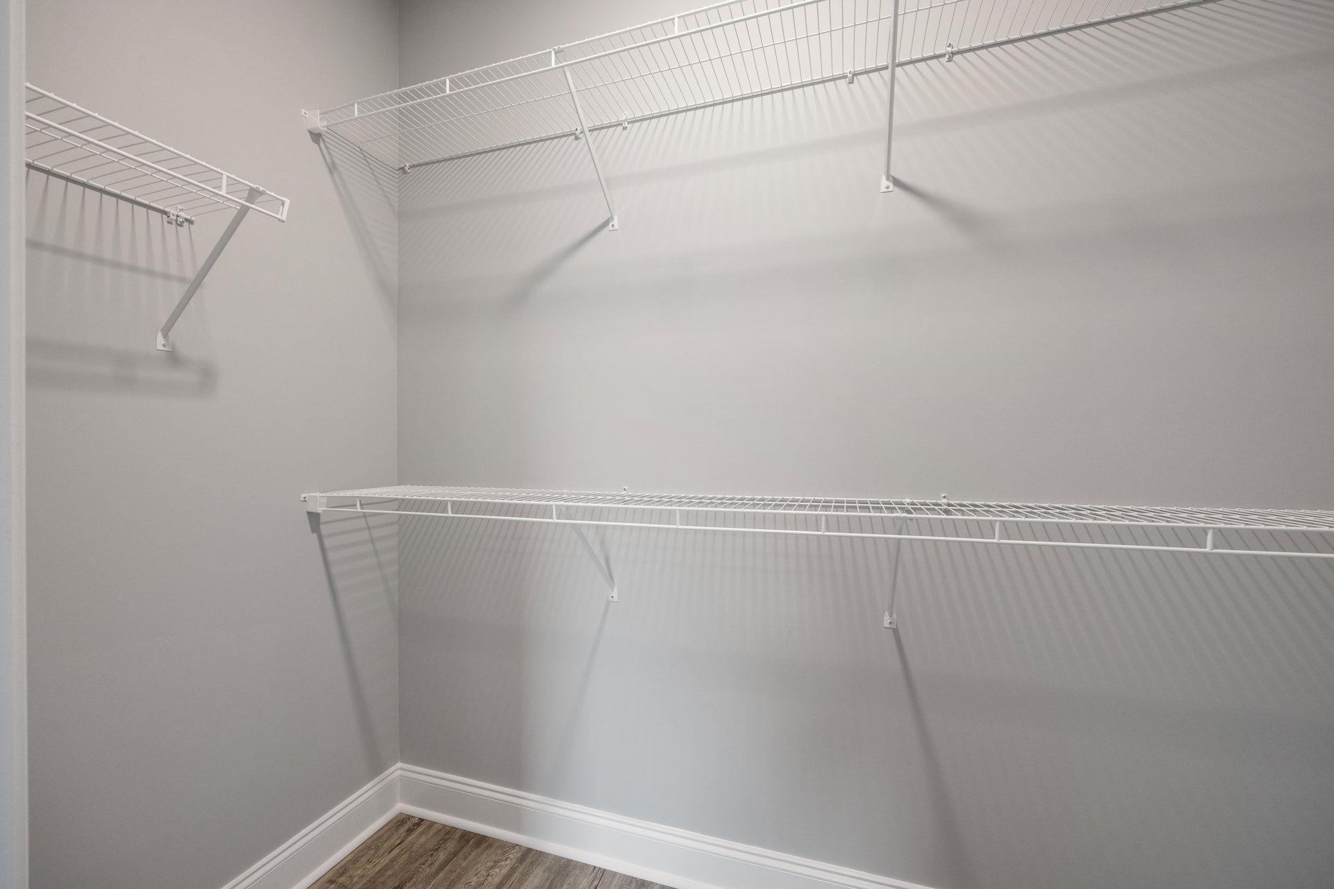 White metal shelf mounted on plaster bathroom wall above tiled floor.