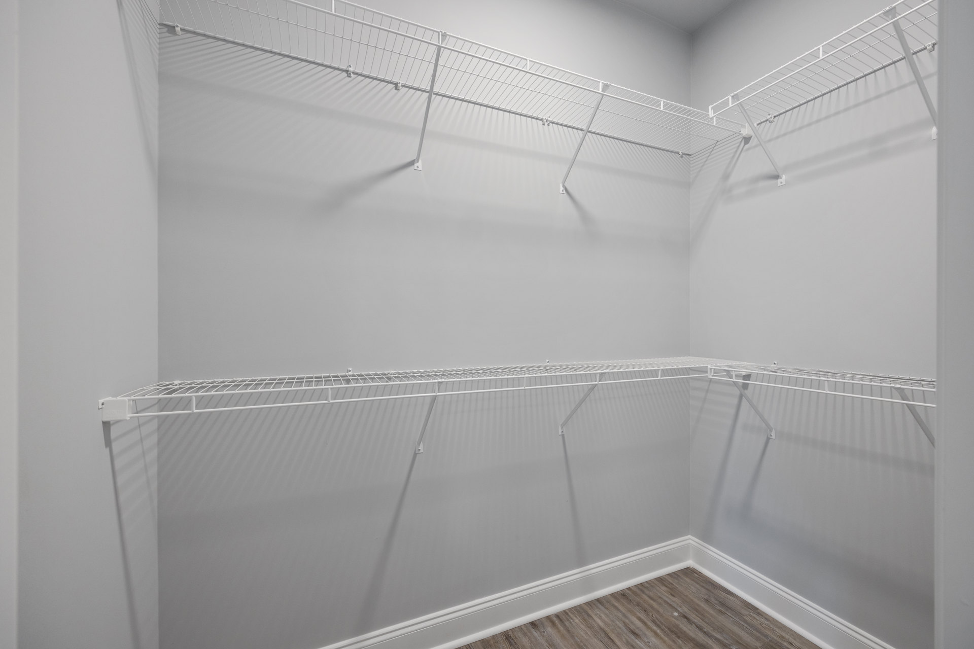 Bathroom with white plaster walls, built-in white shelves, wood flooring, and a walk-in shower.