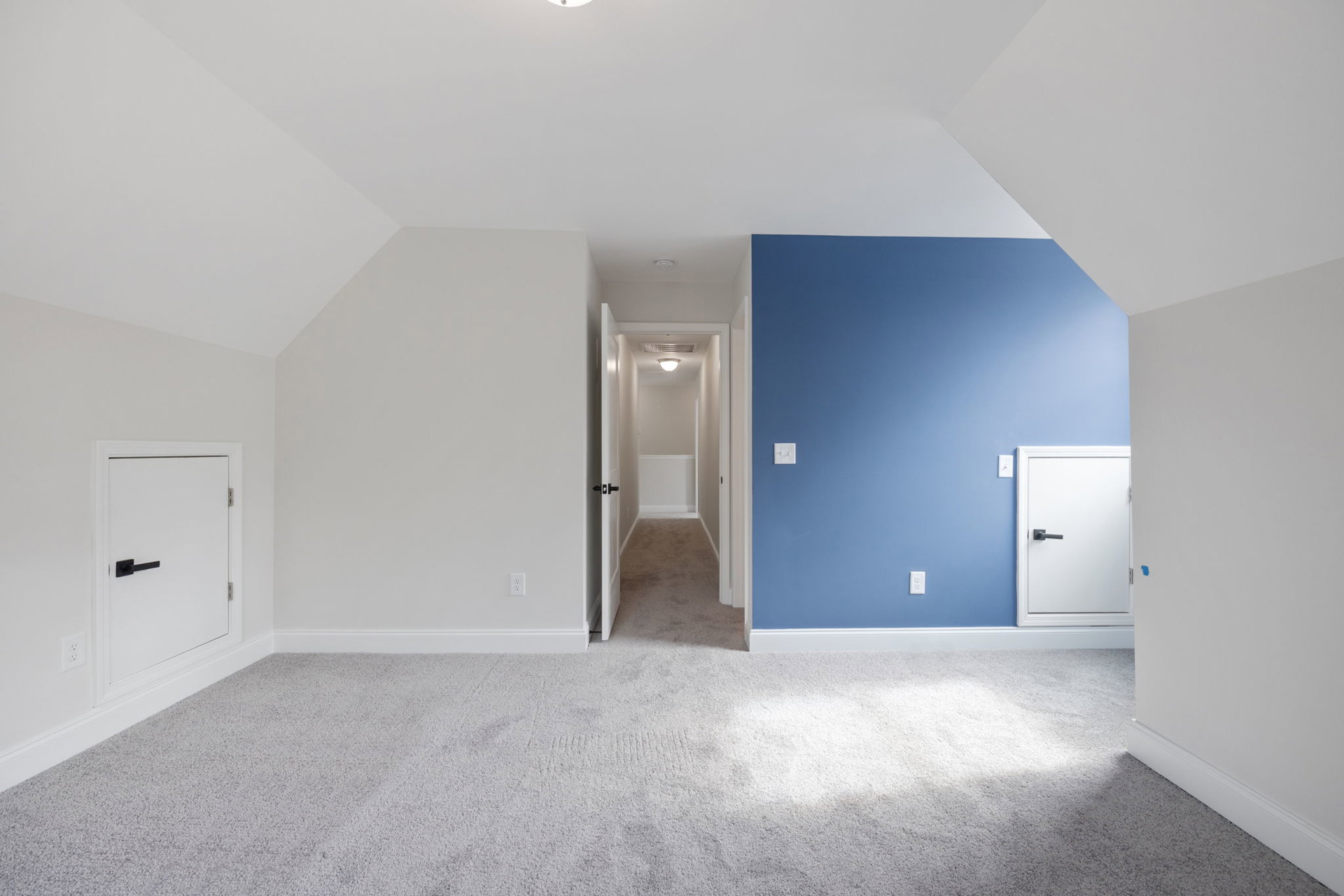 Blue accent wall with white surrounding walls, white door featuring black handle, light switch on white wall, plush white carpet flooring