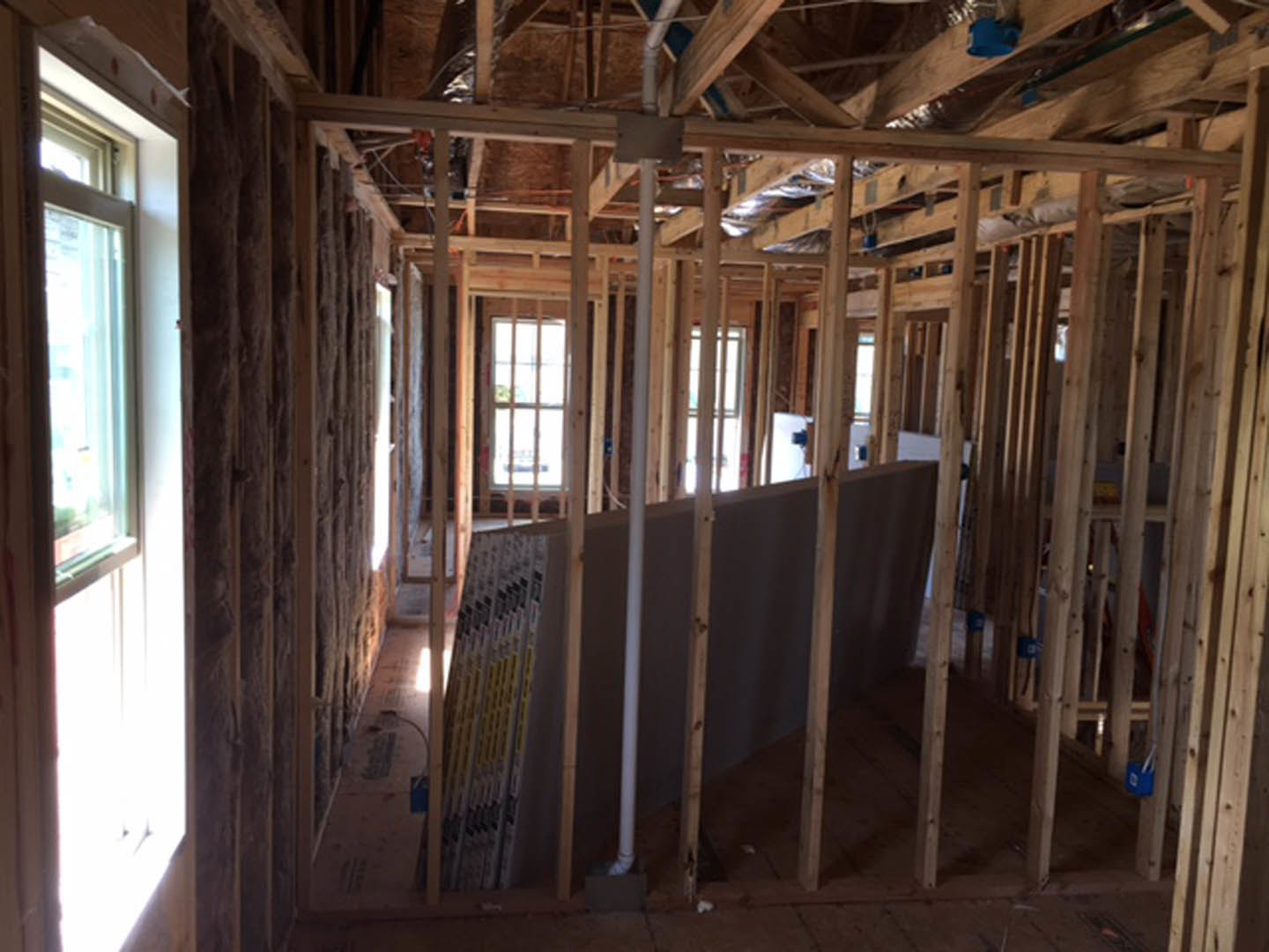 Framed room with exposed wooden beams, unfinished walls, and large windows letting in natural light