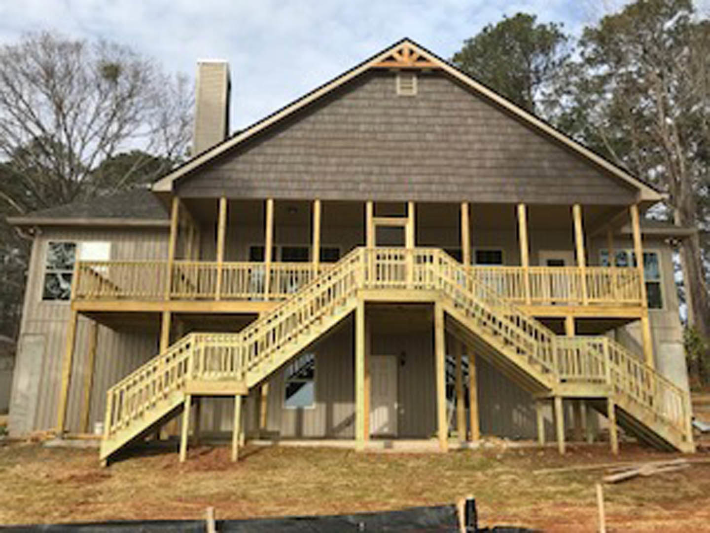 White siding home with wooden porch stairs, surrounded by trees, Sánchez Adobe Park visible in the background.