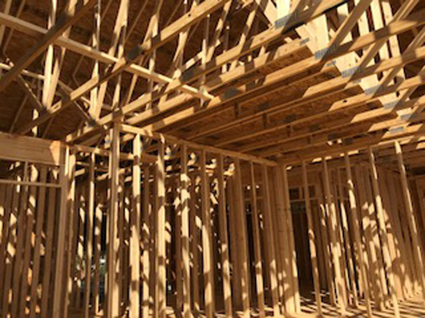 Exposed wooden beams and planks forming the structural frame of a house under construction, with a blurred window opening visible