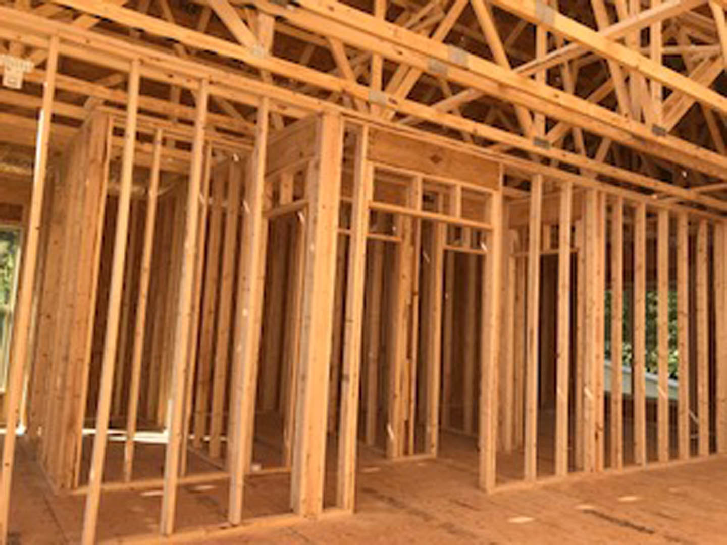 Exposed wooden framing with vertical beams and horizontal planks inside a partially constructed residential home