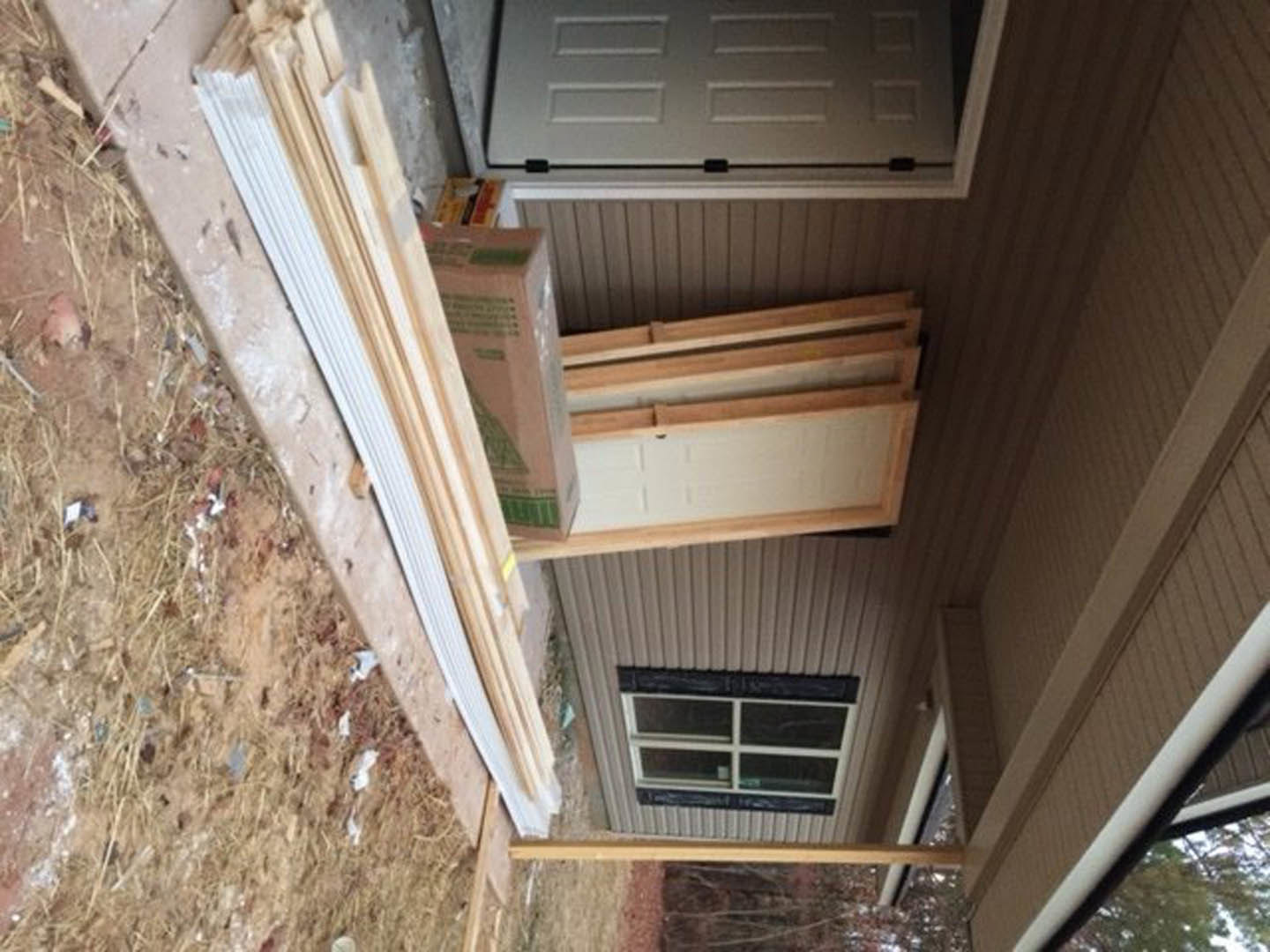 Modern home exterior with horizontal wood plank siding, dark entry door, and adjacent window reflecting sunlight