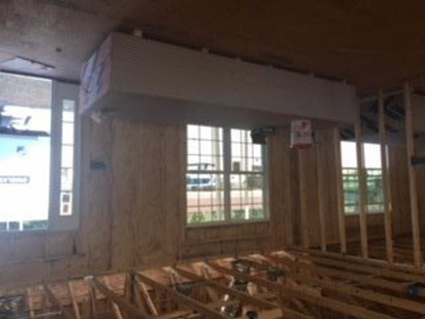 Living room with exposed wood ceiling beams, large windows, and natural daylight illuminating neutral walls.