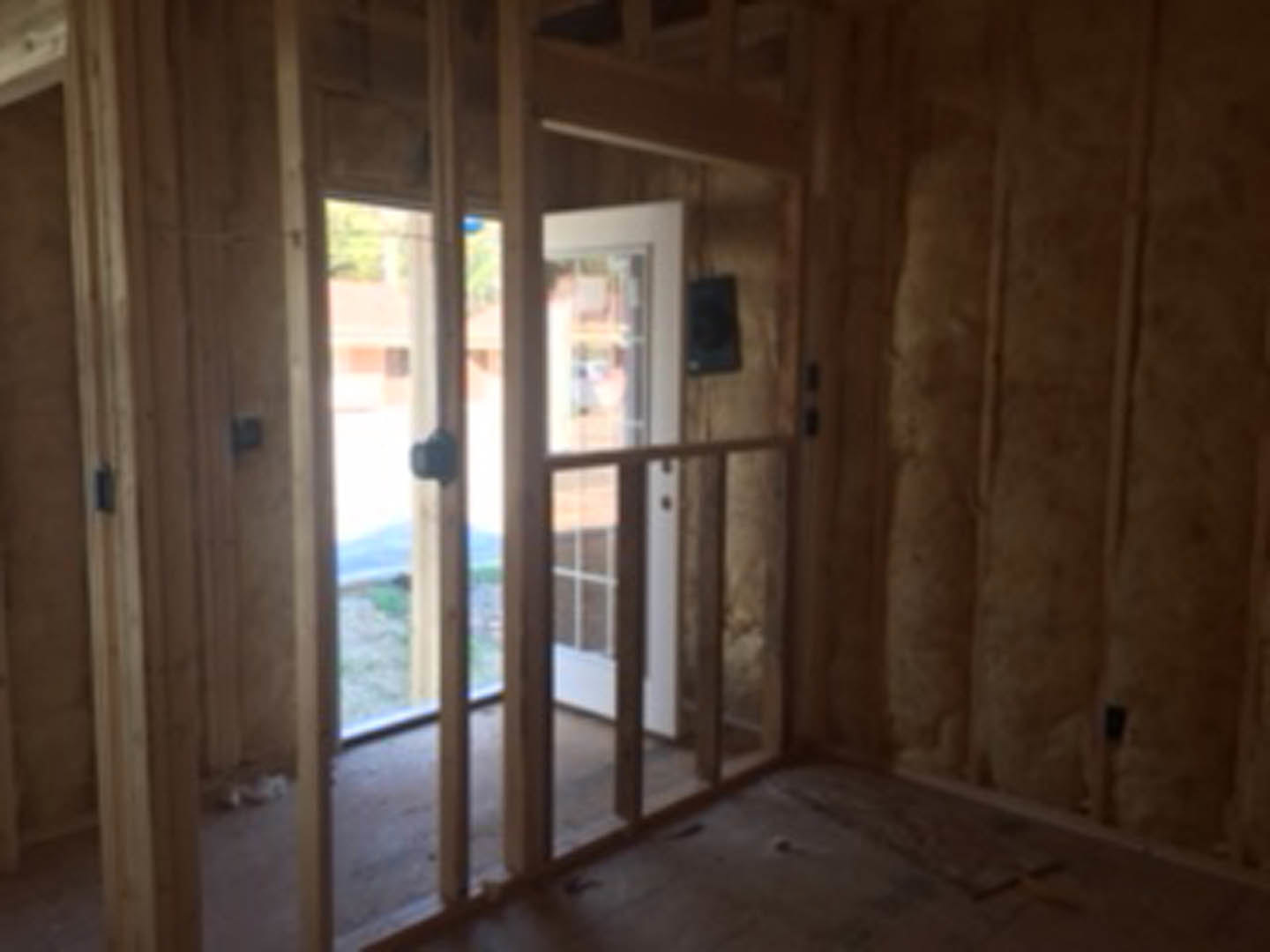 Hardwood plank flooring, white walls, glass-paneled door, large windows letting in natural light