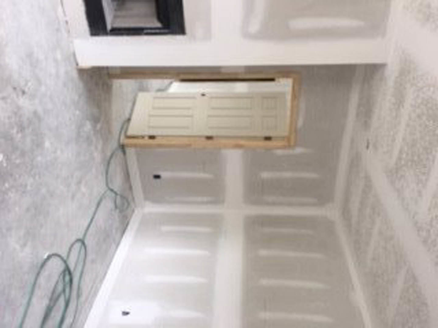 White plaster walls with a wooden door, bathroom sink, and glass shower enclosure in a modern residential interior