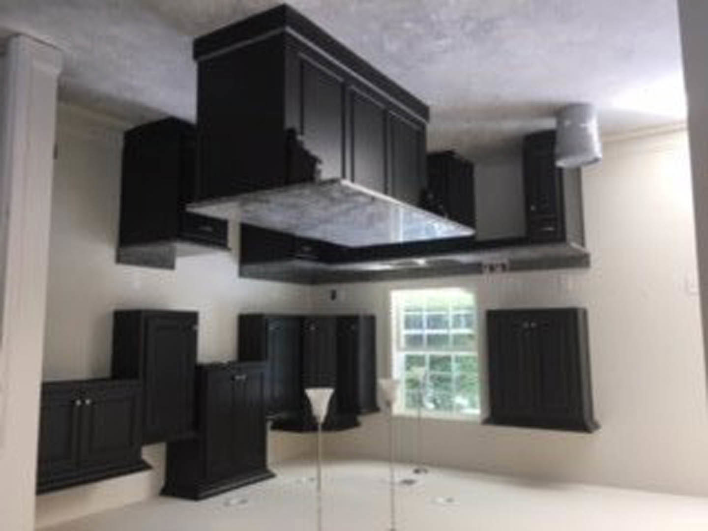 Kitchen with matte black cabinets, white walls, stainless steel range hood, light countertops, and recessed ceiling lighting