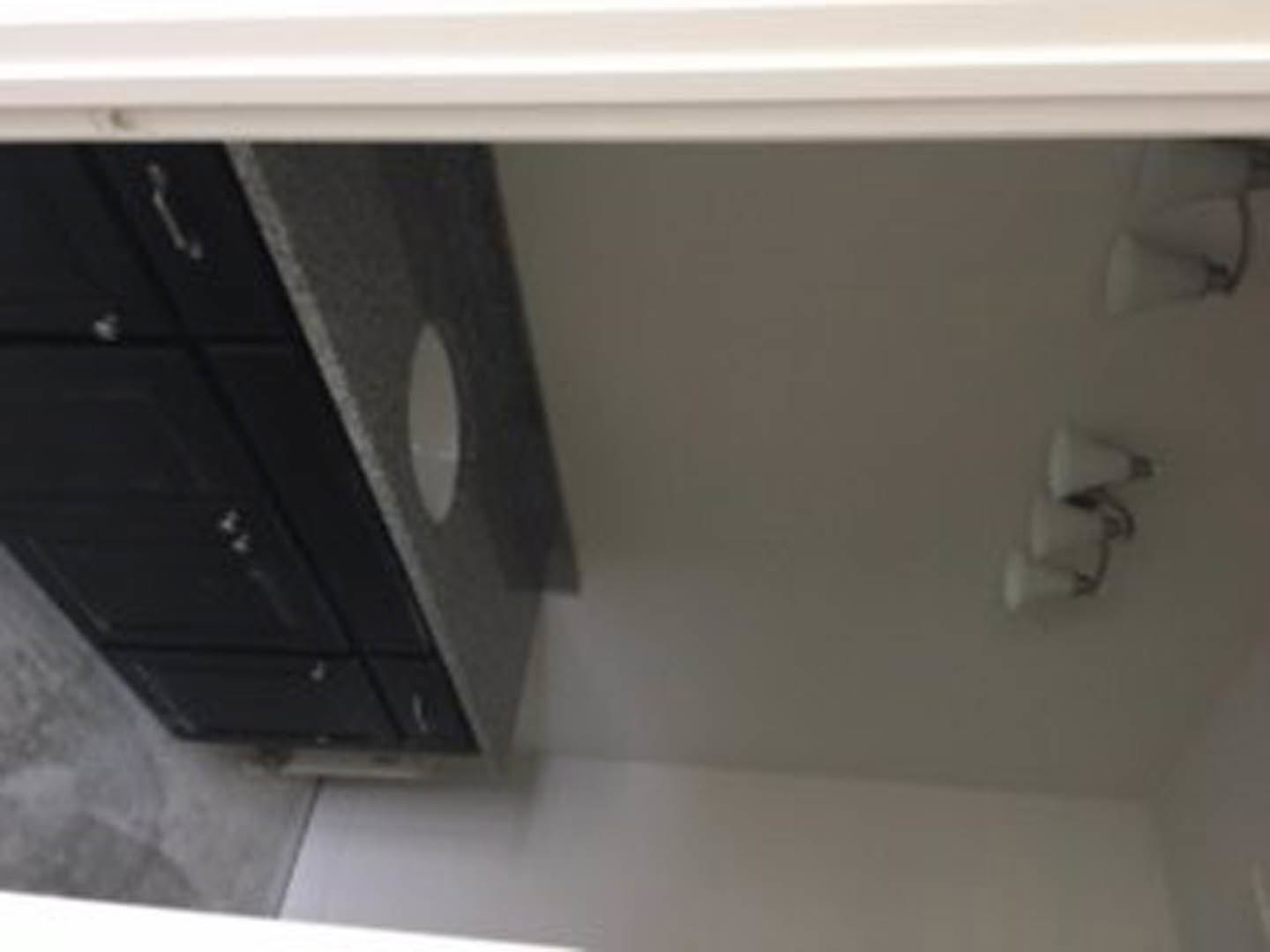 Modern bathroom featuring a white rectangular sink set into wood cabinetry, light-colored walls, and a blurred overhead light fixture.
