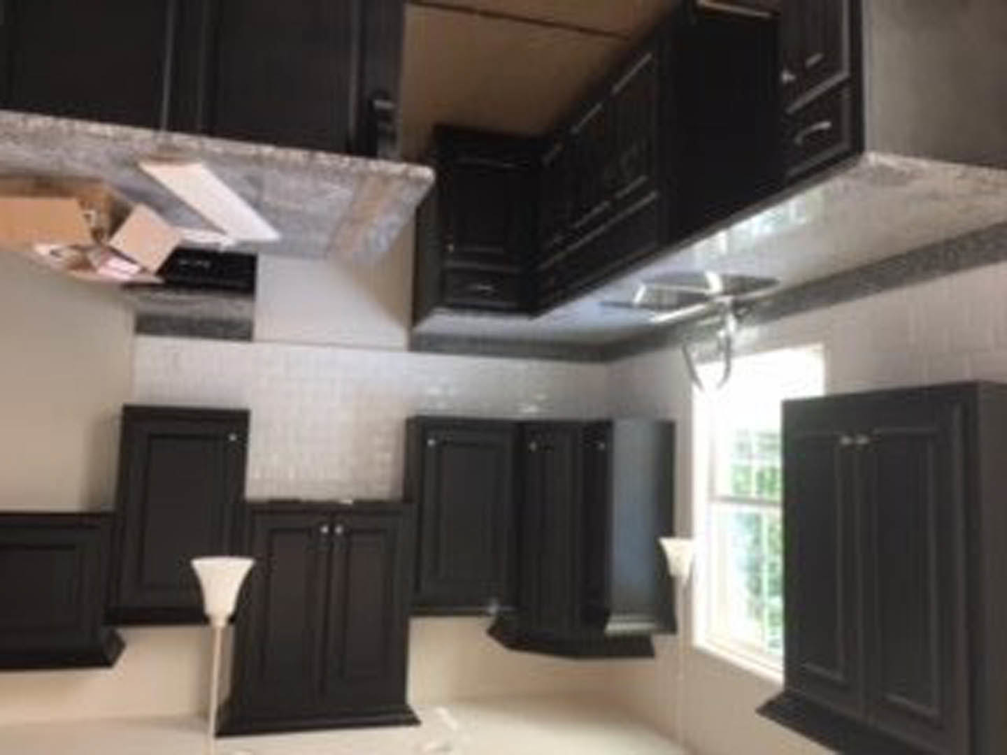 Modern kitchen featuring matte black cabinets, white quartz countertops, stainless steel appliances, and a deep undermount sink beneath a light-colored backsplash