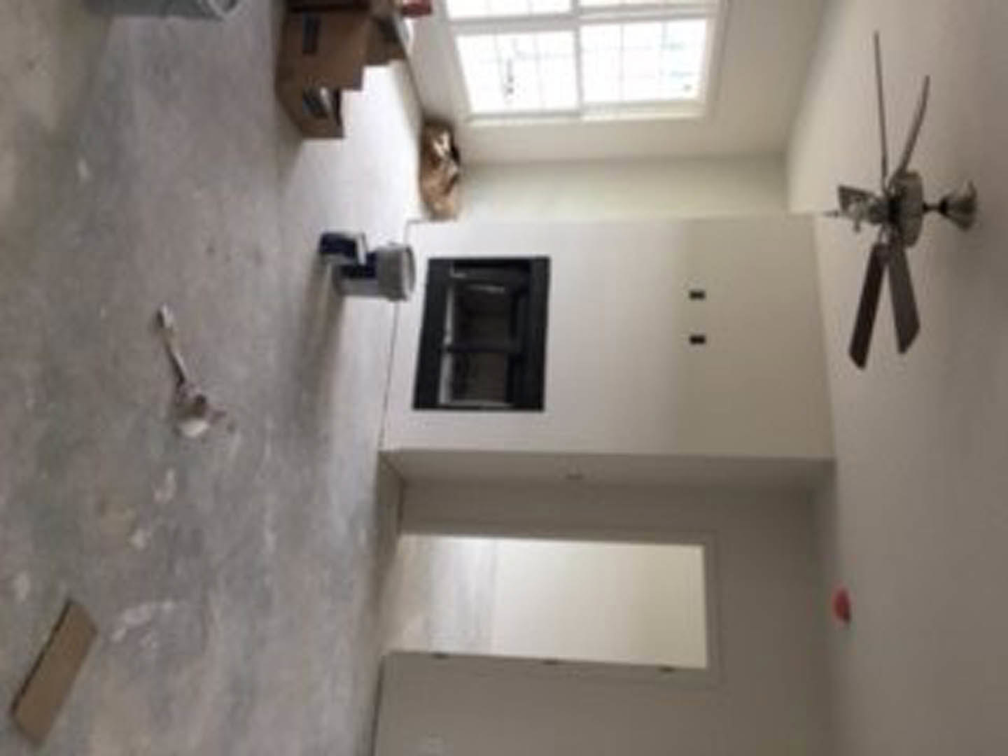 White plaster wall with large window, light wood floor, ceiling fan with metal fixture, minimal modern interior