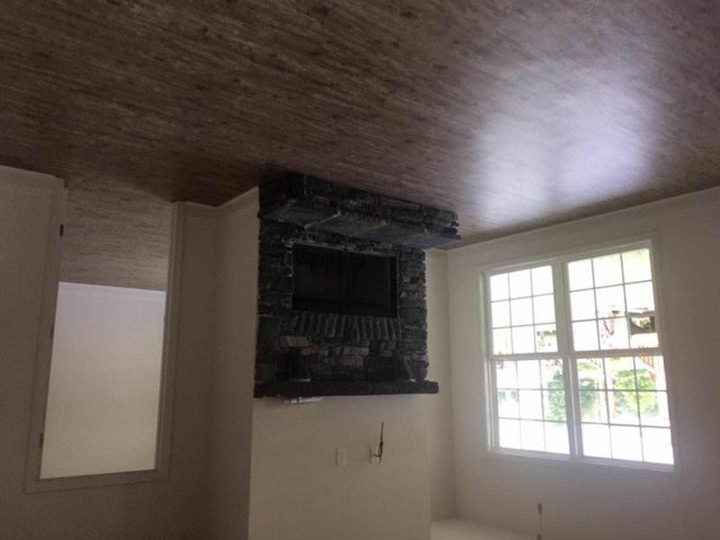 Brick fireplace with black rectangular insert, multi-pane window, white plaster walls, and ceiling in a residential living room.