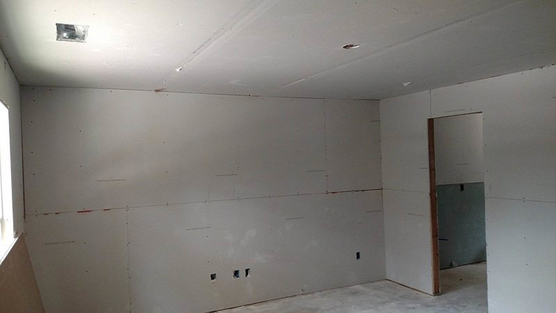 White-walled room with smooth plaster finish, white ceiling, and a simple door; soft lighting highlights clean surfaces.