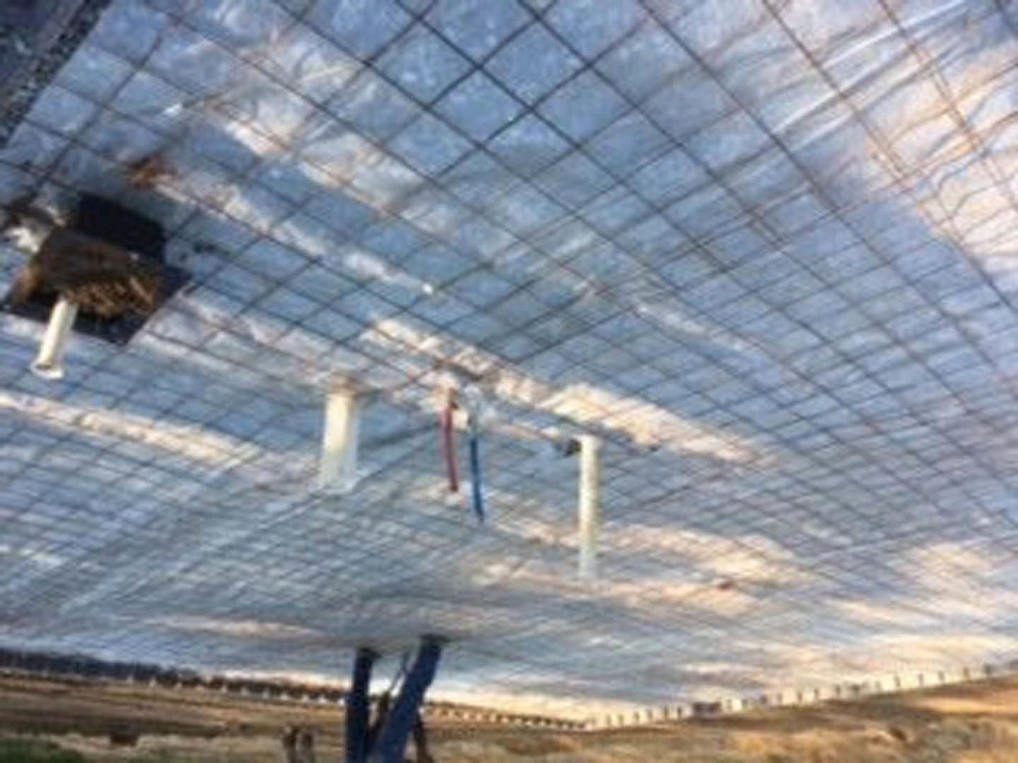 White sheet with blue and red stripes draped outdoors beneath a partly cloudy sky, grid pattern visible on fabric