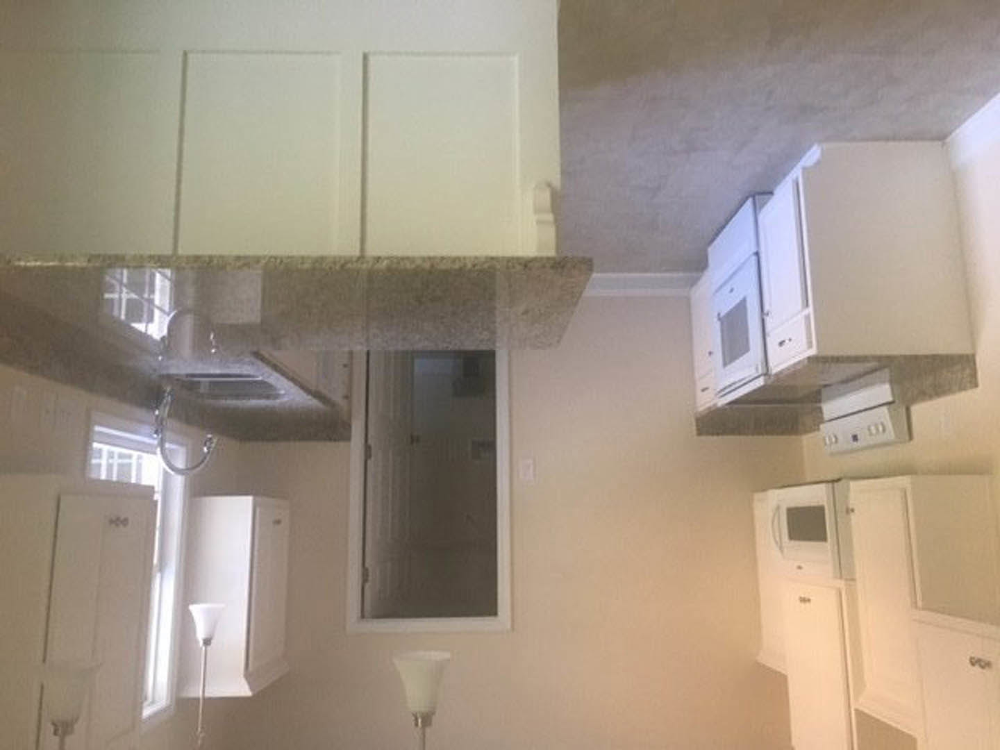 Bright kitchen featuring white appliances, white cabinetry, light countertops, and a window above the sink.