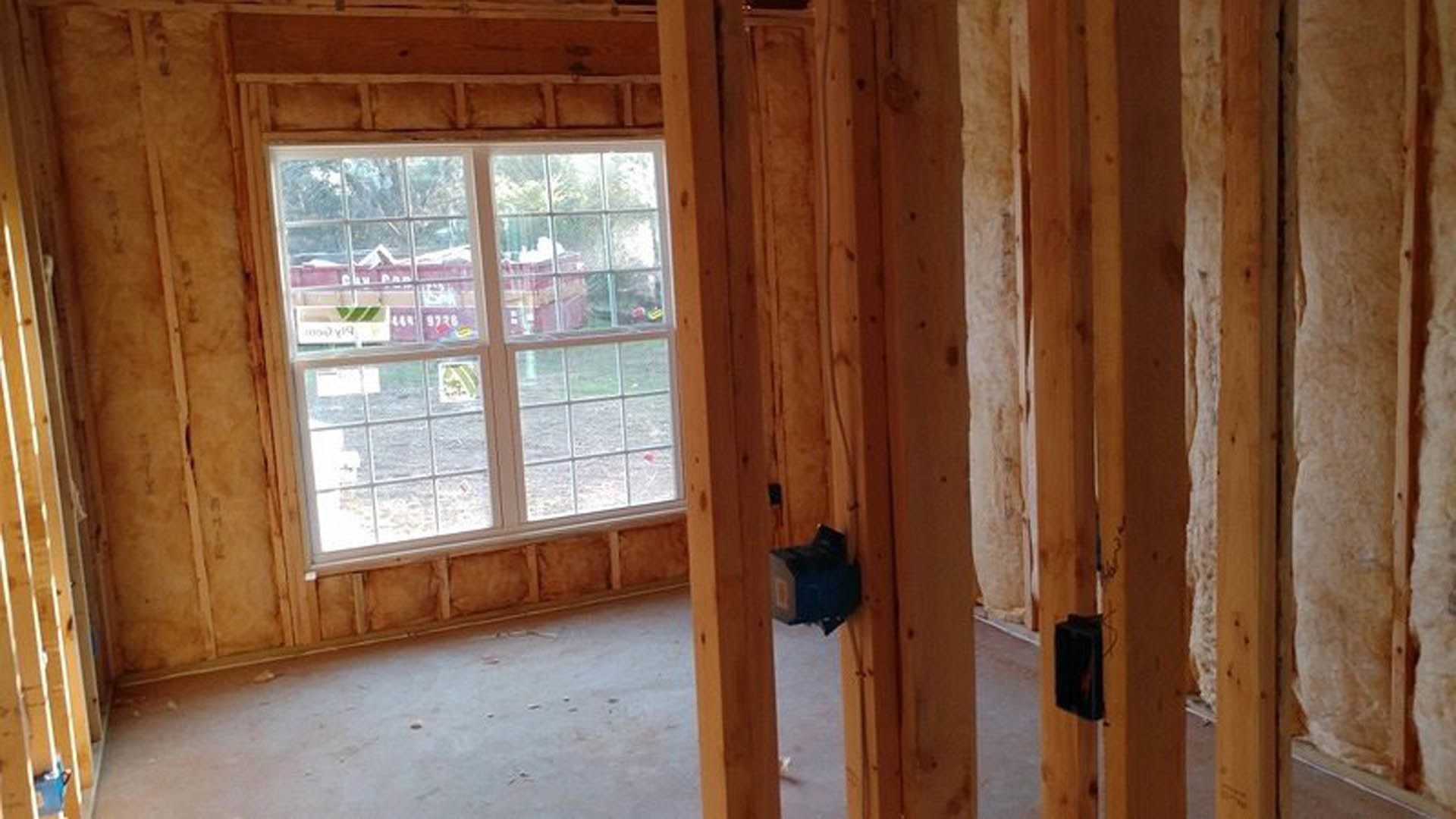 Bedroom with wood plank flooring, exposed ceiling beams, large window with glass panes, and neutral painted walls
