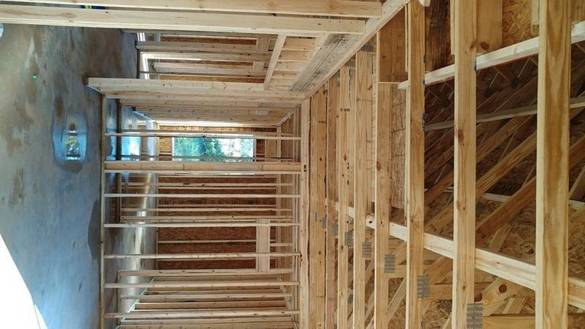 Exposed wooden framing with beams, planks, and insulation in a partially constructed residential interior
