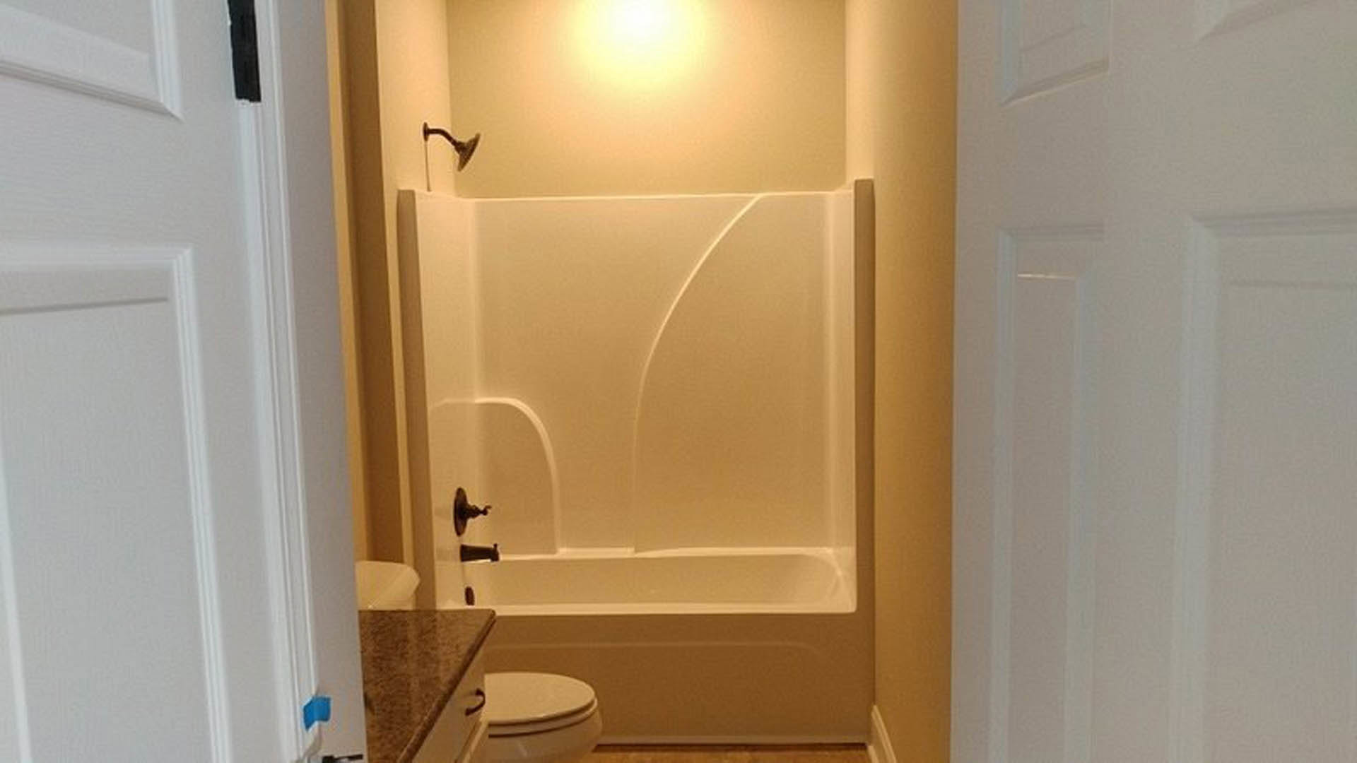 Modern bathroom with freestanding bathtub, white toilet, light gray tile flooring, and neutral tiled walls