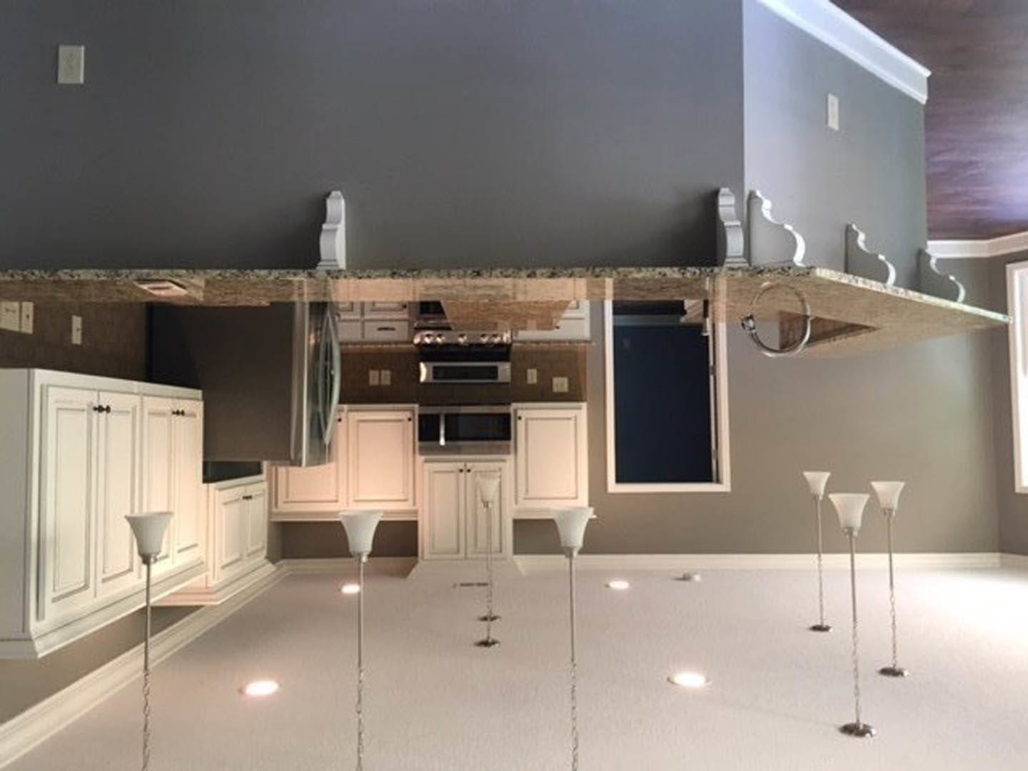 White kitchen cabinets with sleek hardware, light stone countertop, stainless steel sink, built-in microwave, smooth white ceiling with recessed lighting, neutral painted walls.