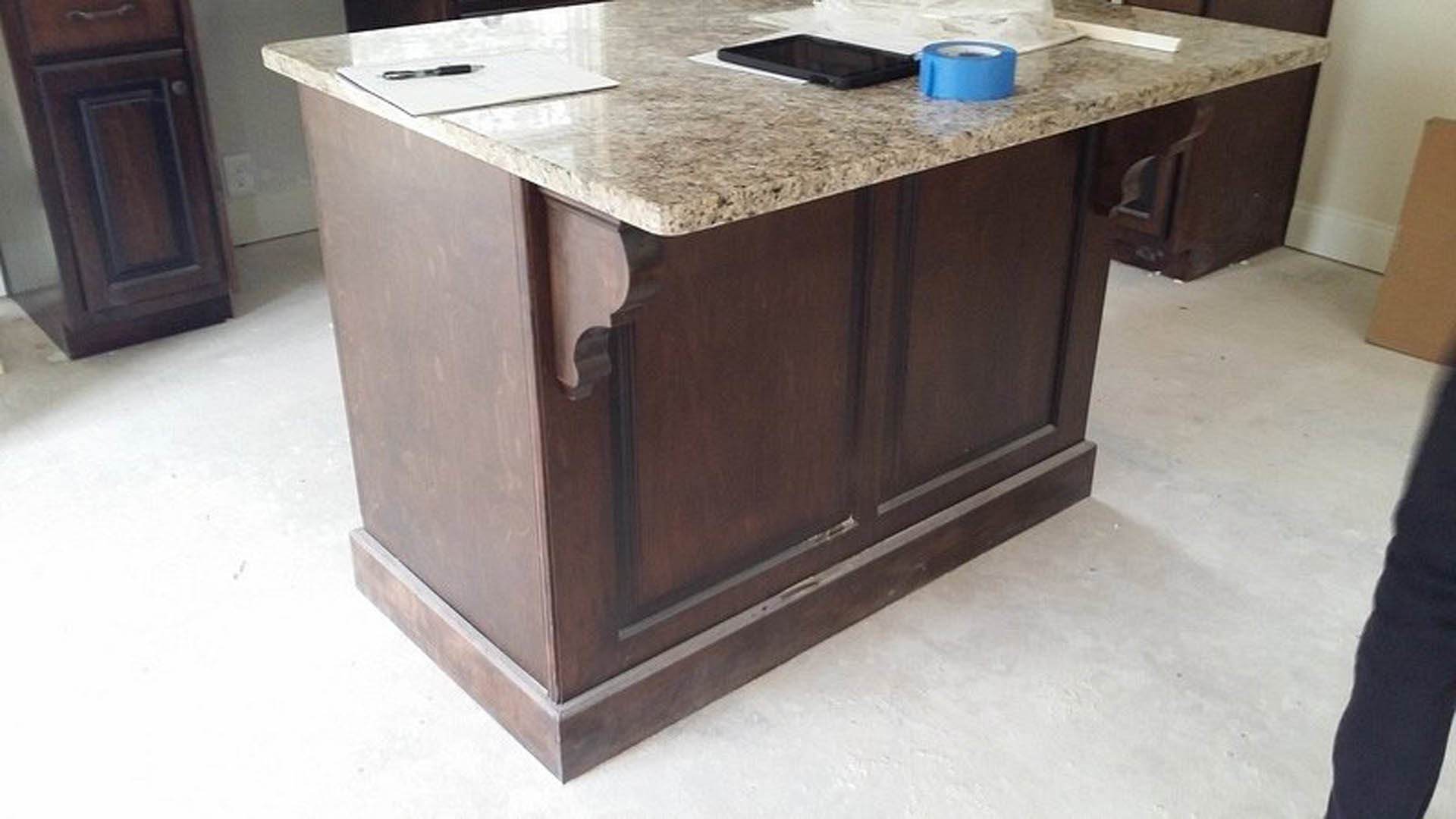 Marble-topped kitchen island with wooden cabinetry, stainless steel appliances, and light hardwood flooring