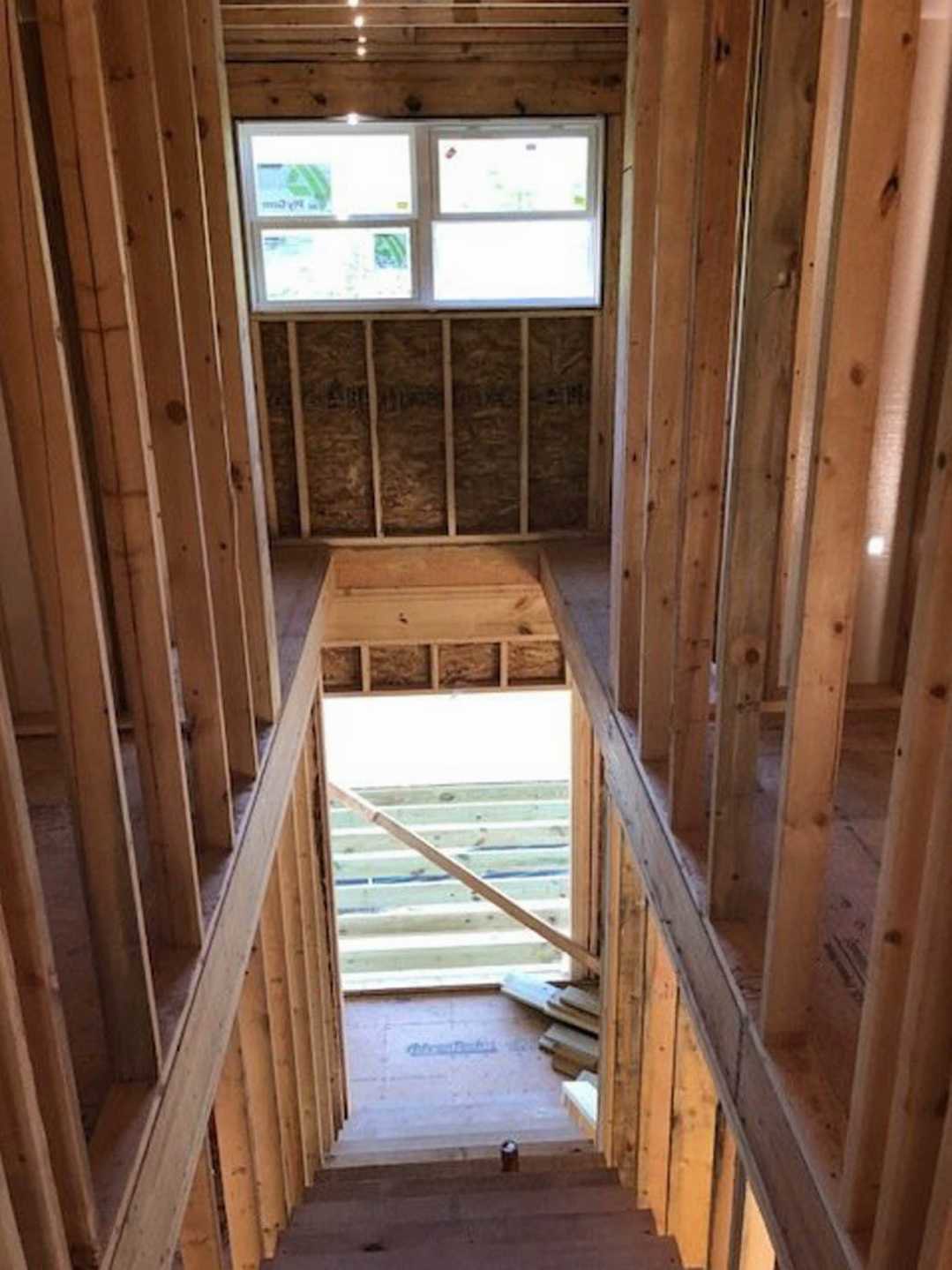 Wood-framed window set in a room with wooden ceiling, stone flooring, and wooden wall accents, daylight streaming in.