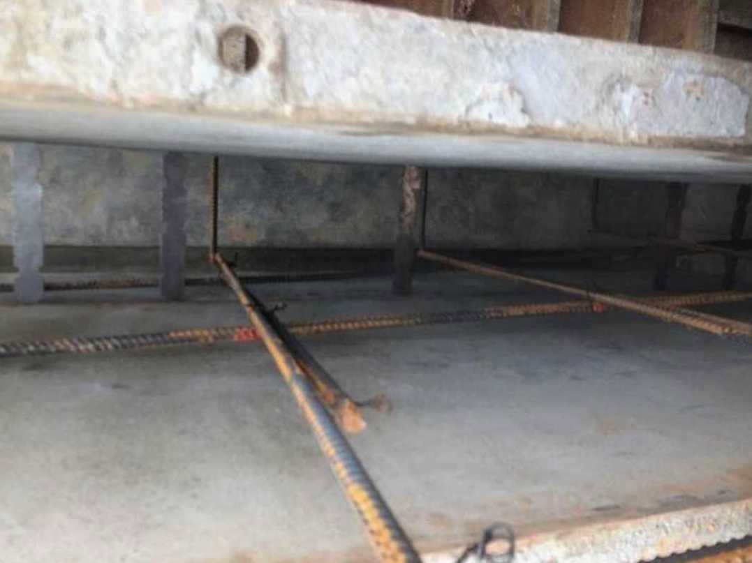 Exposed steel rods embedded in smooth concrete flooring inside a residential space