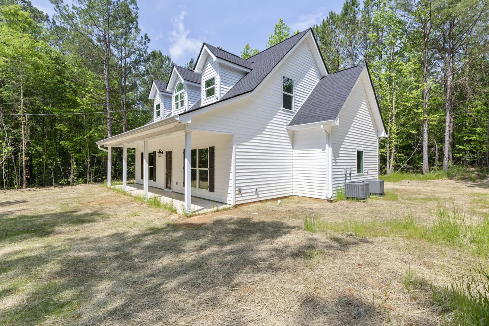 White siding house with spacious covered porch, white railings, grassy front yard, and large windows with white frames