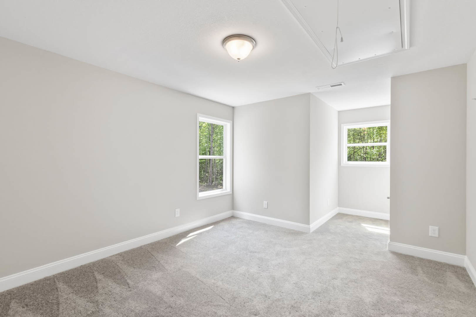 White carpeted room with large windows, ceiling light fixture, and view of trees outside