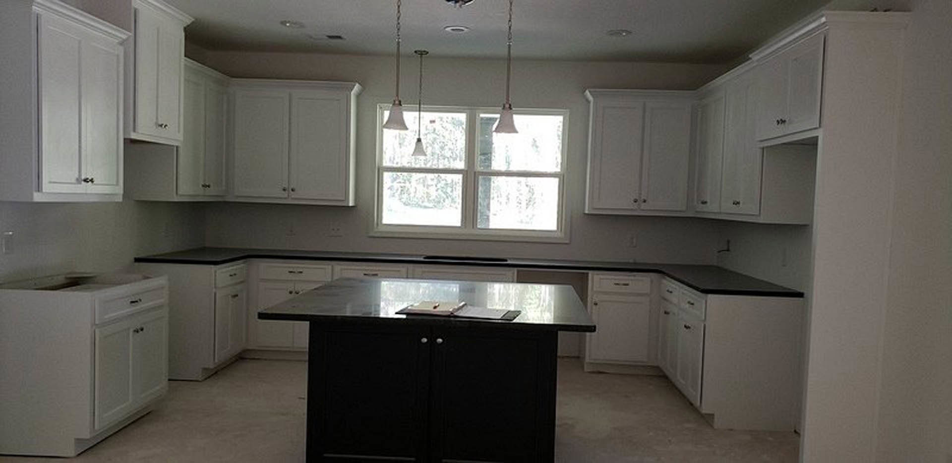 White kitchen cabinets with brushed metal handles, light stone countertops, stainless steel sink, and hardwood flooring.