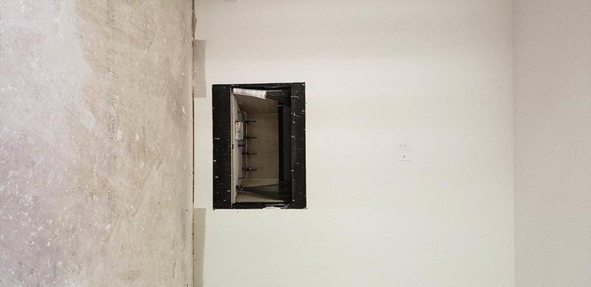 White plaster walls and rectangular window in a minimalist room, with a close-up view of a wooden door