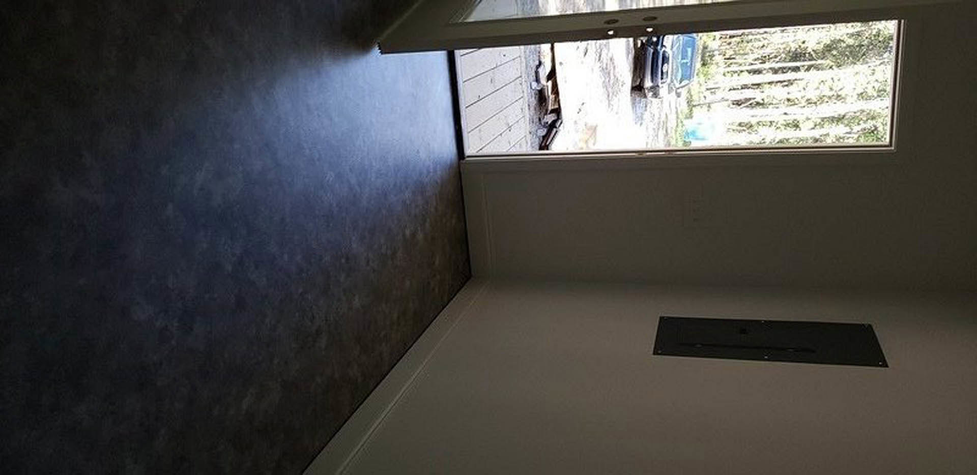 White plaster walls and ceiling, large black-framed glass door, light wood floor, natural daylight streaming in, modern residential entryway