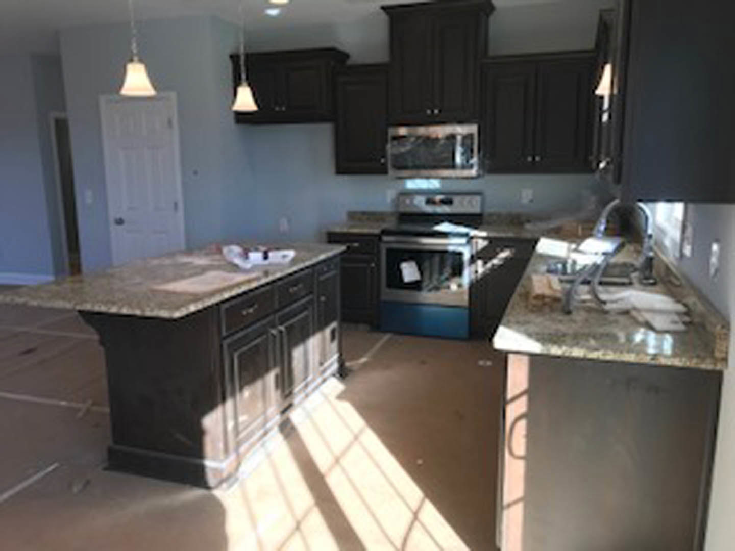 Kitchen featuring dark wood cabinets, granite countertops, stainless steel appliances, undermount sink, and neutral painted walls