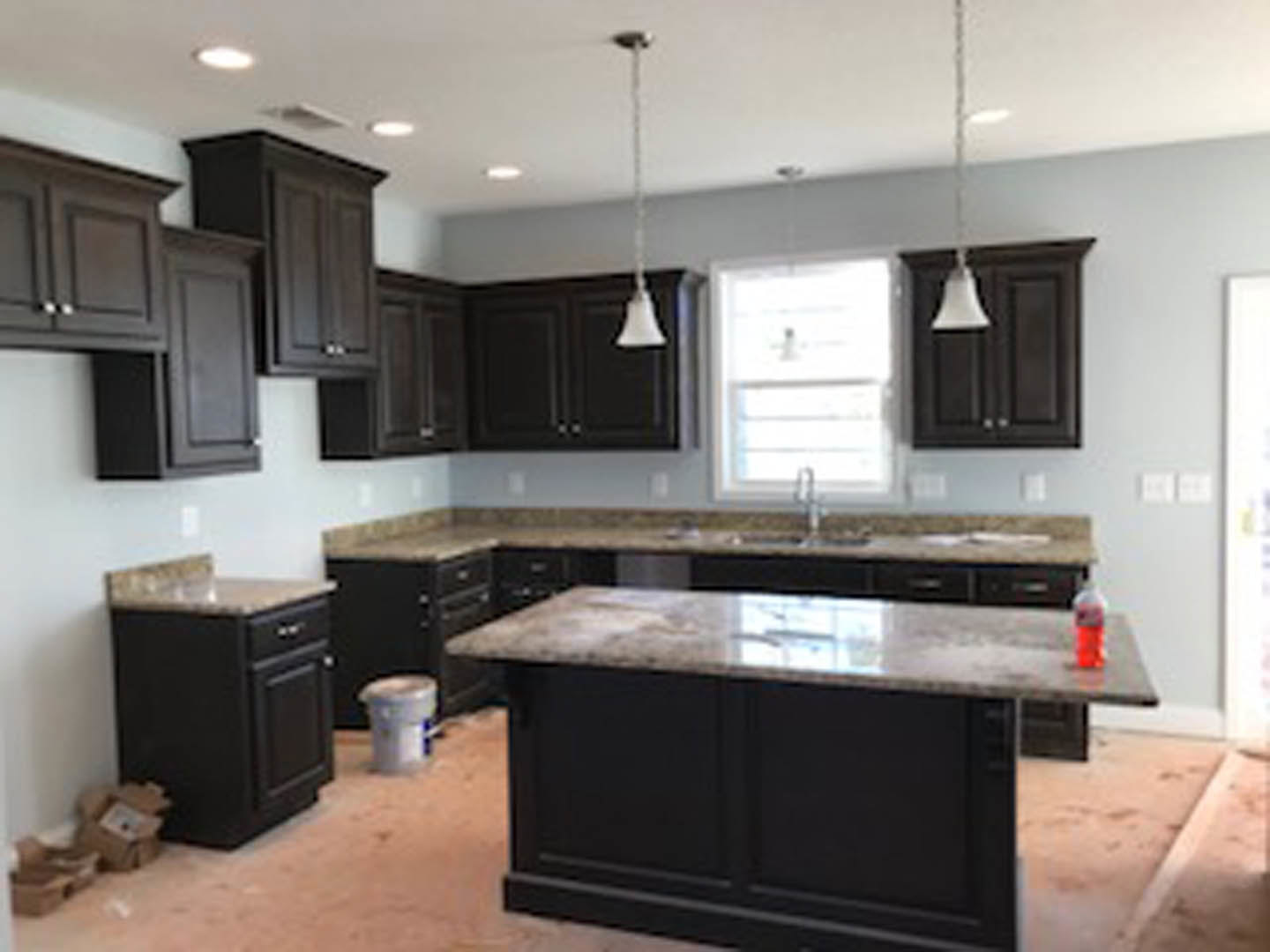 Kitchen with dark wood cabinets, marble countertop, stainless steel appliances, and a window providing natural light