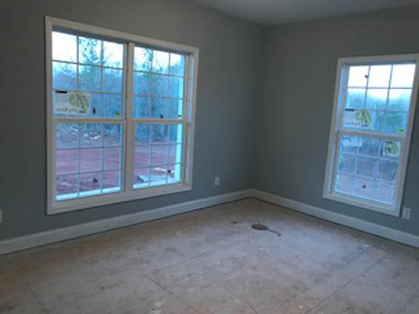 Spacious room featuring large windows with white frames, polished concrete floor, neutral walls, and natural daylight illuminating the interior.