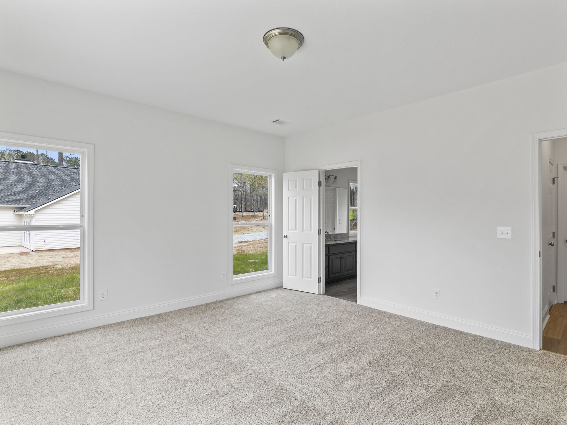 White walls, white door with silver knobs, ceiling light fixture, carpeted floor