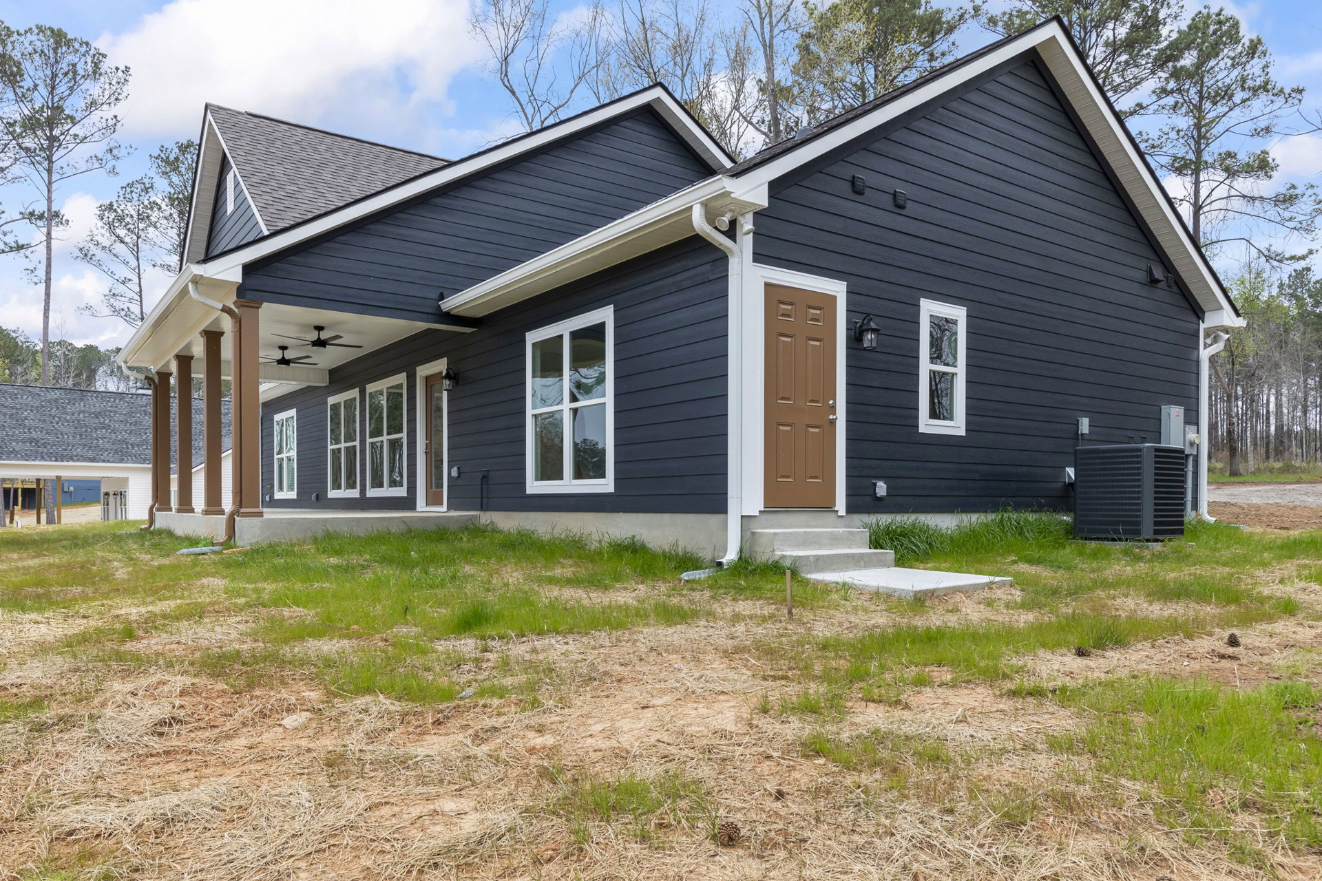 Two-story house with white roof, brown front door, white-framed windows, and green grass lawn